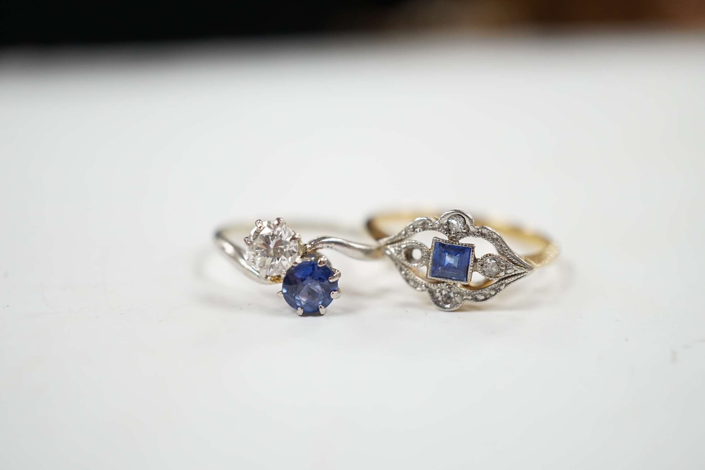 An early 20th century 18ct and plat, sapphire and diamond set cluster ring (stone missing), size N/O and a white metal, sapphire and diamond set two stone crossover ring, size M, gross weight 4.6 grams.